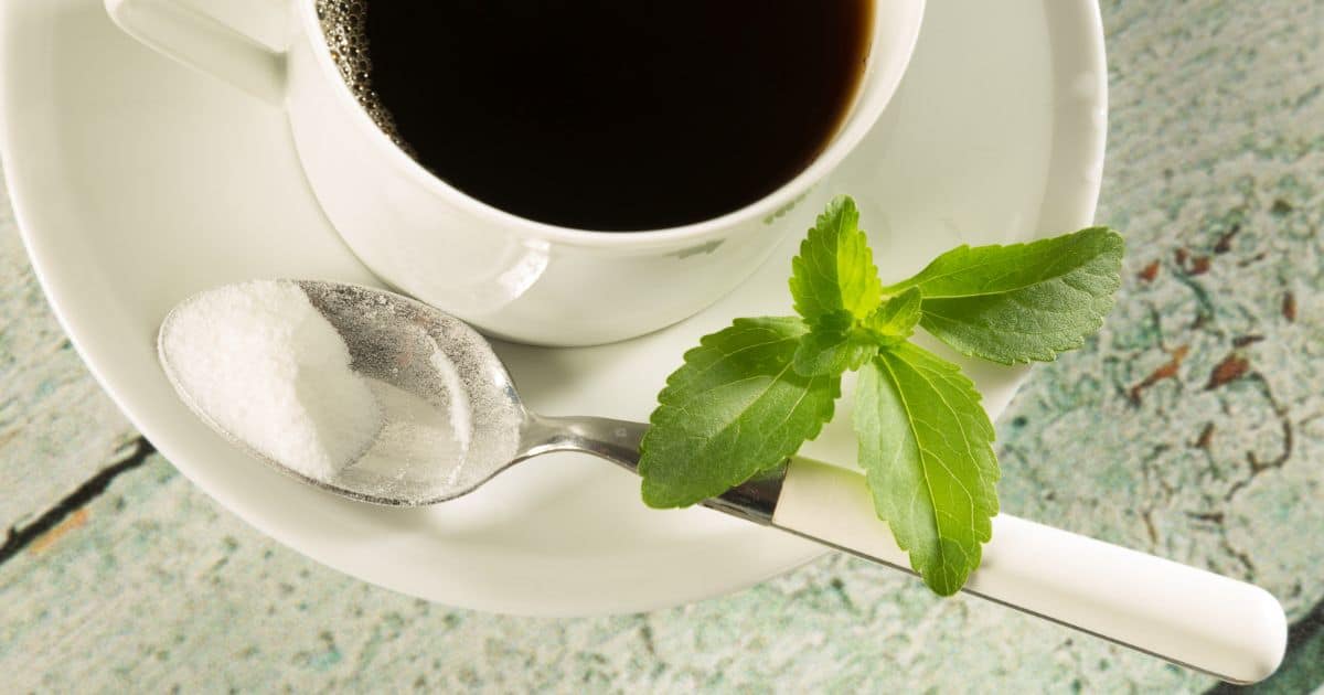 Cup of black coffee with stevia in a spoon with stevia leaves